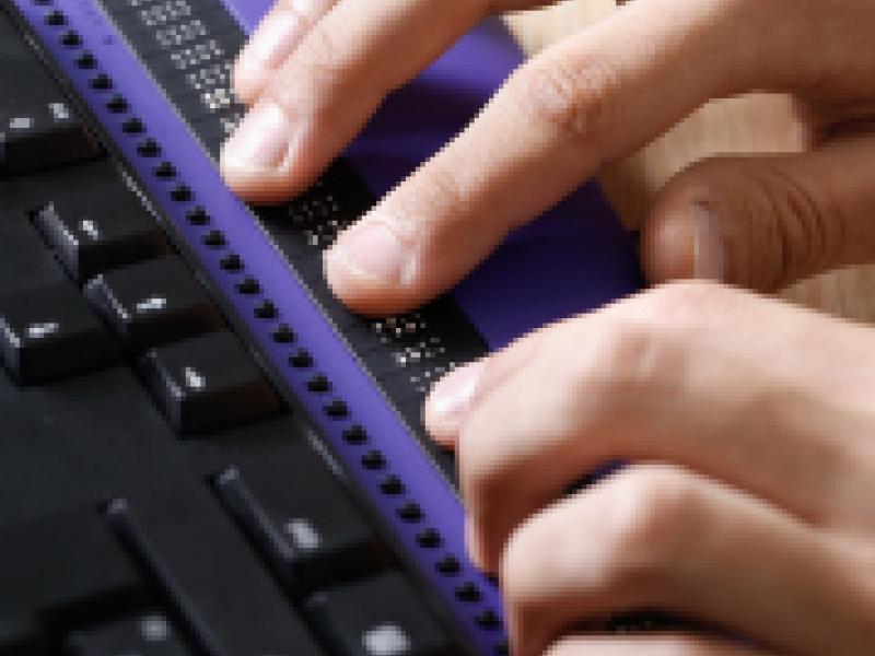 A customer reading braille on a laptop.